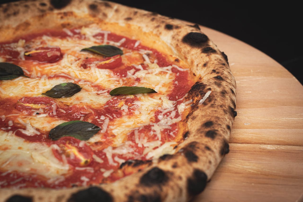 Close-up of a freshly baked Margherita pizza with cheese, basil, and tomato sauce on a wooden board.